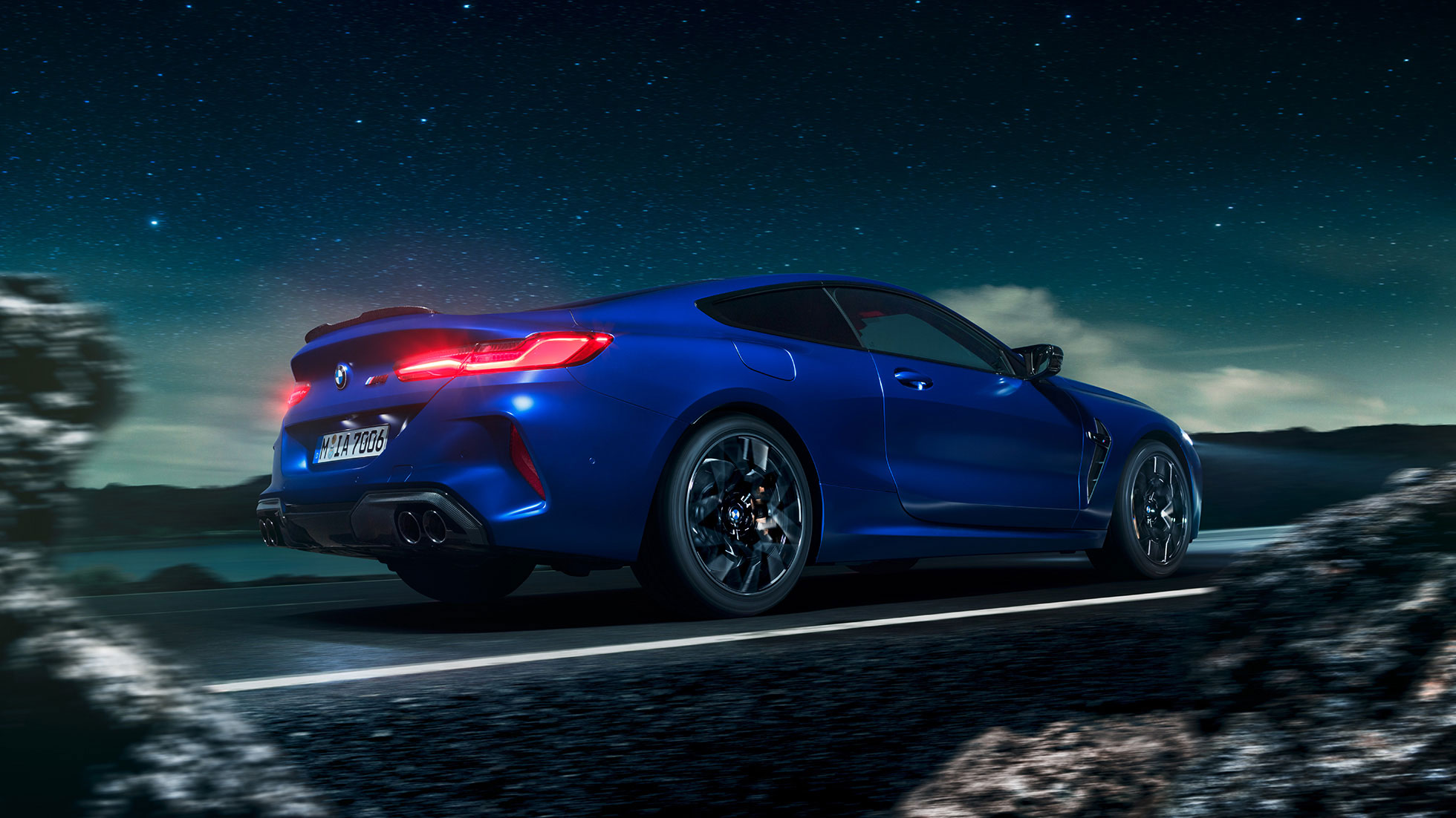 BMW M8 Coupé, three-quarter side view. BMW M8 Coupé in Marina Bay Blue metallic, driving three-quarter side view in front of starry sky.